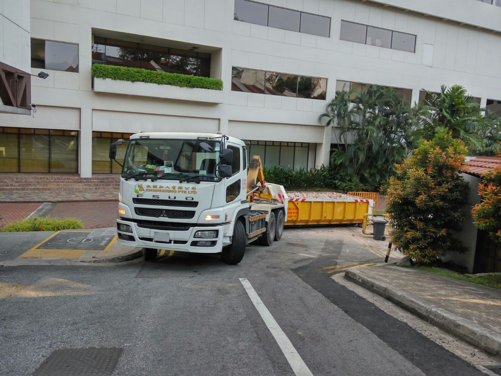 disposal company pick up truck dragging skip bin